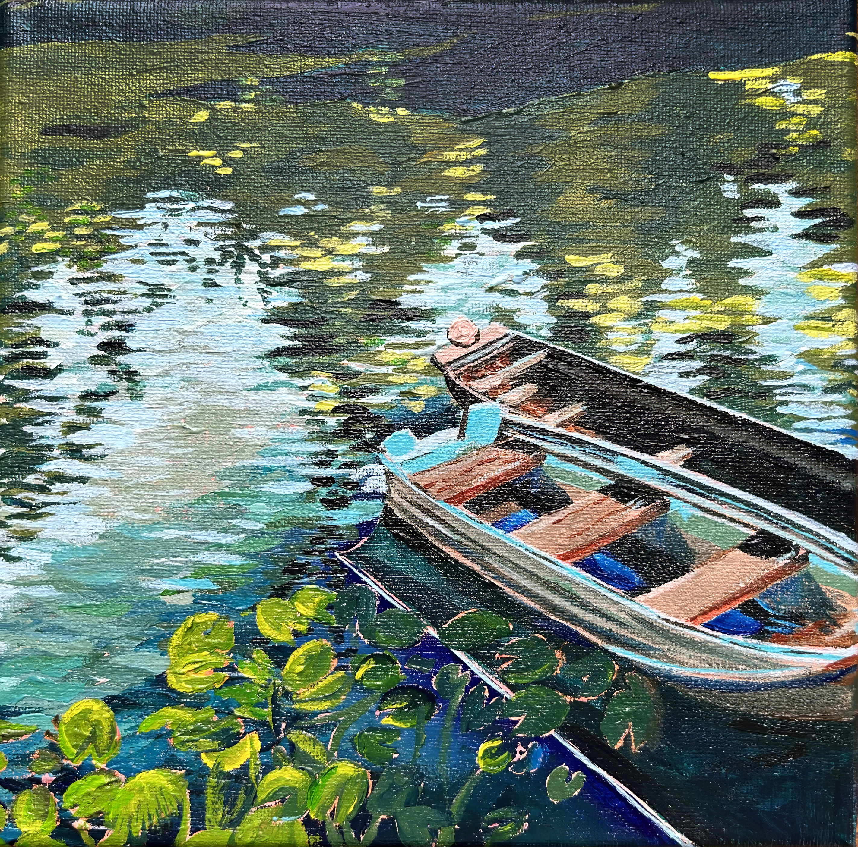 Two empty wooden rowboats, painted colorfully, float beside green lily pads on a shimmering, sunlit river. There are many green, blue, yellow, and brown tones.