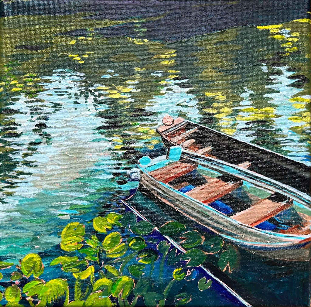 Two empty wooden rowboats, painted colorfully, float beside green lily pads on a shimmering, sunlit river. There are many green, blue, yellow, and brown tones.