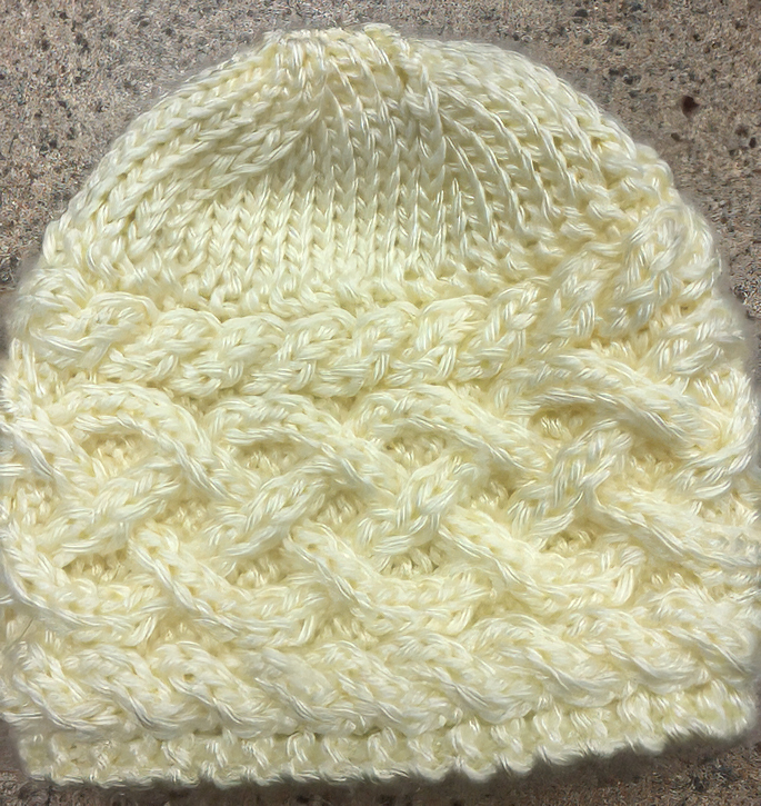 Knit cream-white hat with an ornate geometric design going all the way around.